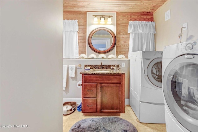 laundry area with washing machine and clothes dryer, wooden walls, sink, and wooden ceiling