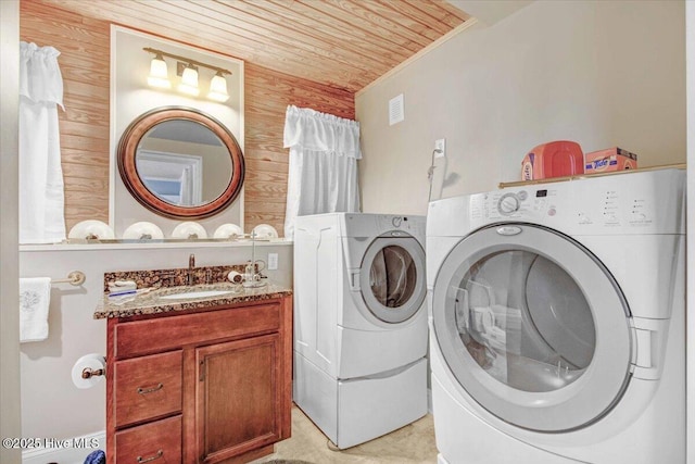 clothes washing area with separate washer and dryer, wood walls, sink, and wood ceiling