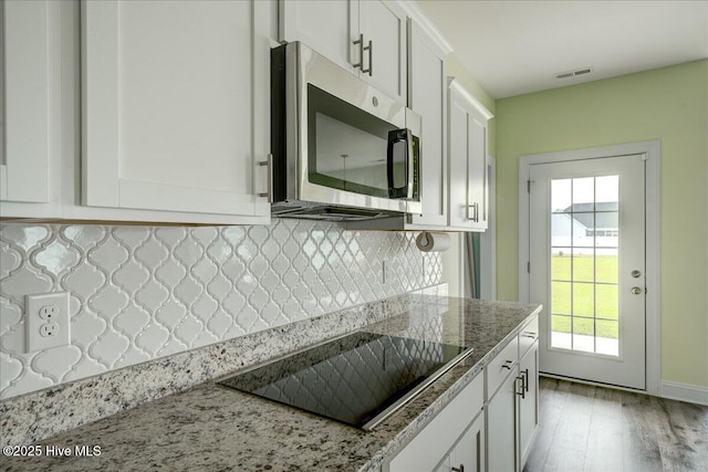 2022 Tarpon Trl, New Bern, NC 28562 - kitchen with stainless steel microwave, black electric cooktop, white cabinets, and tasteful backsplash
