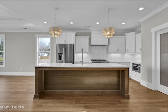 kitchen with a kitchen island, white cabinetry, premium range hood, and appliances with stainless steel finishes