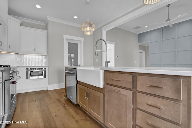 kitchen featuring white cabinets, appliances with stainless steel finishes, hanging light fixtures, and sink