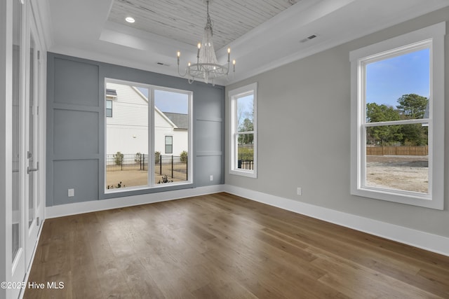 interior space featuring hardwood / wood-style flooring, a raised ceiling, crown molding, and a chandelier