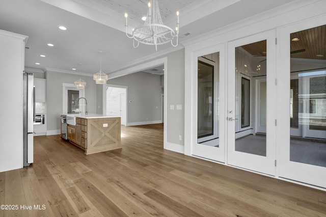 kitchen with pendant lighting, a kitchen island with sink, crown molding, stainless steel refrigerator, and a chandelier