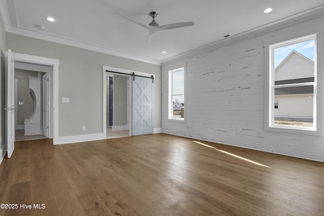 unfurnished bedroom with hardwood / wood-style floors, ceiling fan, a barn door, and crown molding