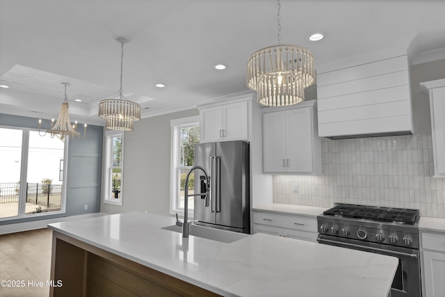 kitchen featuring high end appliances, a center island with sink, decorative light fixtures, light stone counters, and white cabinetry