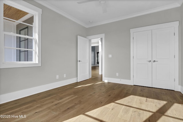 unfurnished bedroom with hardwood / wood-style flooring, ceiling fan, crown molding, and a closet