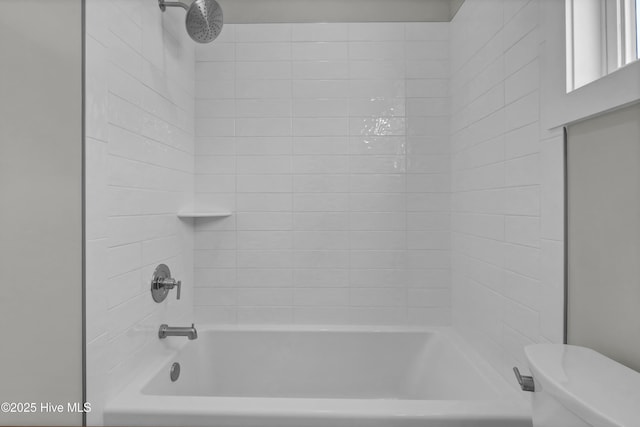 bathroom with toilet and tiled shower / bath