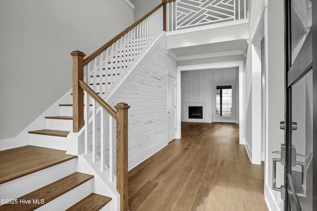 stairs featuring a towering ceiling, hardwood / wood-style flooring, and a tiled fireplace