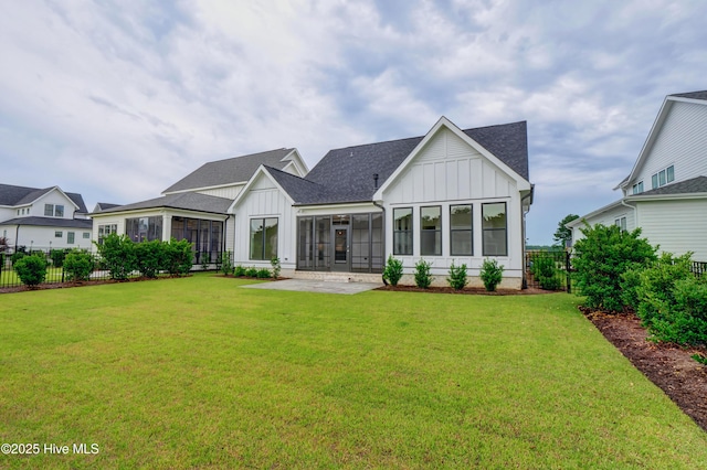 rear view of house featuring a sunroom, a patio area, and a lawn