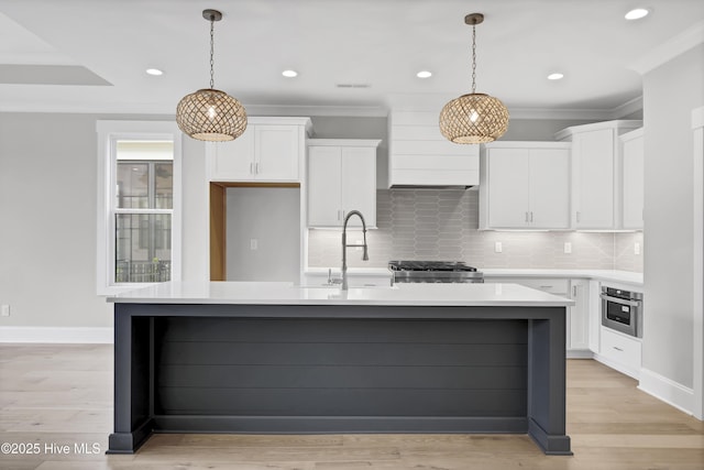 kitchen featuring white cabinets, stove, and an island with sink