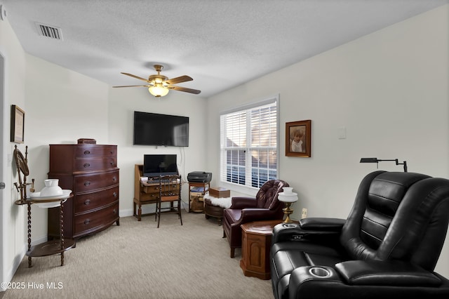 sitting room with ceiling fan, light colored carpet, and a textured ceiling