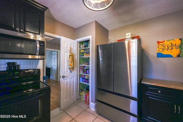 kitchen with a textured ceiling, stainless steel appliances, and light tile patterned flooring