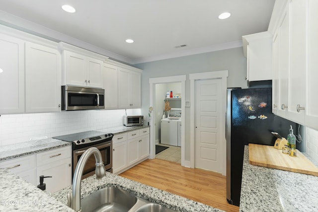 kitchen with light stone countertops, stainless steel appliances, separate washer and dryer, decorative backsplash, and white cabinets