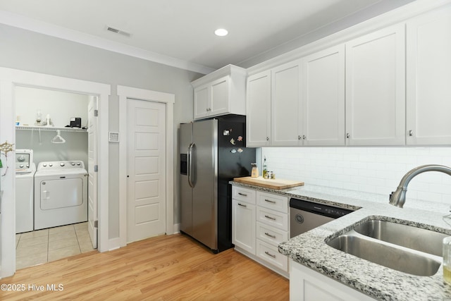 kitchen featuring sink, stainless steel appliances, separate washer and dryer, decorative backsplash, and white cabinets