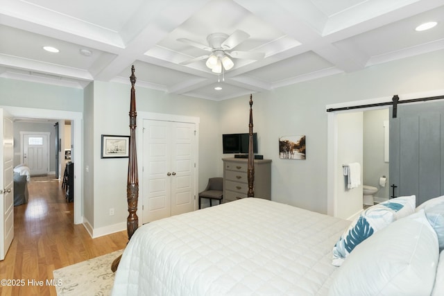 bedroom with coffered ceiling, ceiling fan, a barn door, beamed ceiling, and a closet