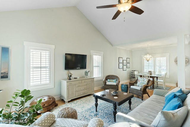 living room with high vaulted ceiling, ceiling fan with notable chandelier, and light wood-type flooring