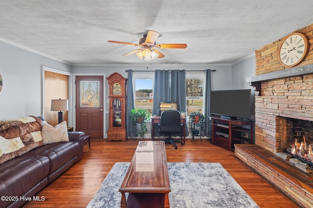 living room with hardwood / wood-style flooring, ceiling fan, ornamental molding, and a textured ceiling