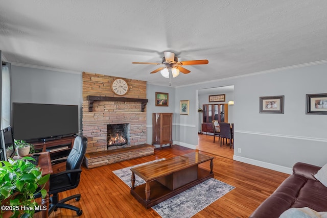 living room with a stone fireplace, crown molding, wood-type flooring, and a textured ceiling