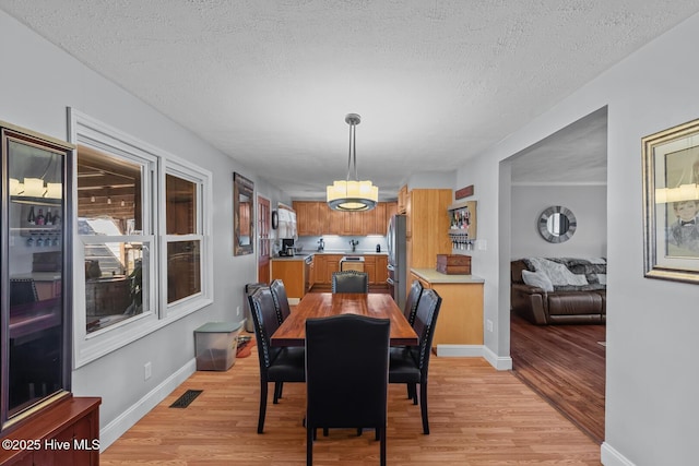 dining room with a textured ceiling and light hardwood / wood-style flooring