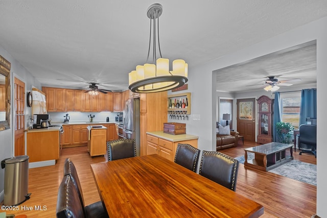 dining room with ceiling fan, light hardwood / wood-style flooring, and a textured ceiling