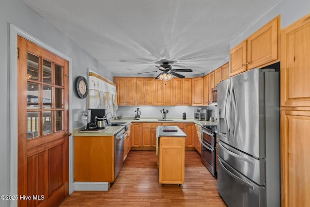 kitchen featuring ceiling fan, light brown cabinets, stainless steel appliances, light hardwood / wood-style flooring, and a kitchen island