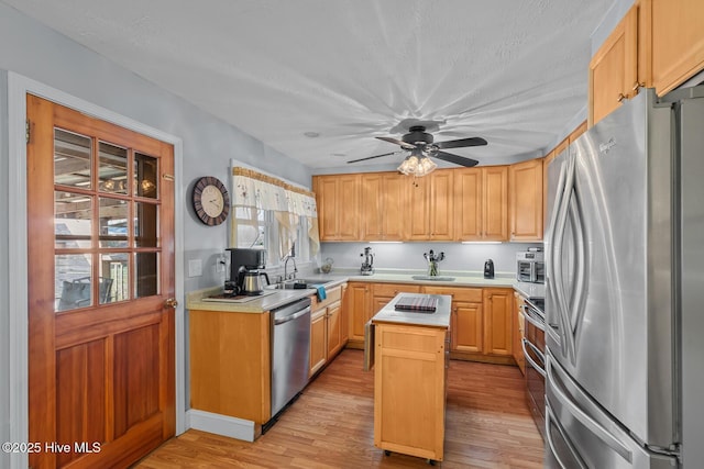 kitchen featuring a kitchen island, light wood-type flooring, light brown cabinets, and appliances with stainless steel finishes