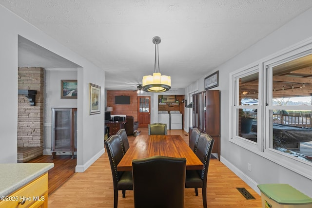 dining space with ceiling fan, independent washer and dryer, a textured ceiling, and light hardwood / wood-style flooring