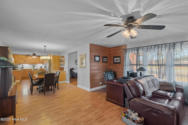 living room with a textured ceiling, light wood-type flooring, and ceiling fan