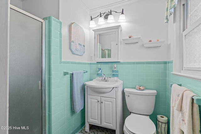 bathroom with crown molding, toilet, a shower with door, vanity, and tile walls