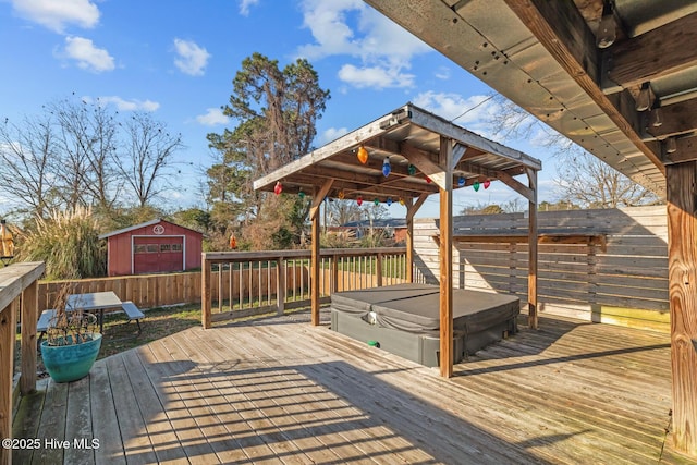 wooden terrace featuring a covered hot tub and a storage shed