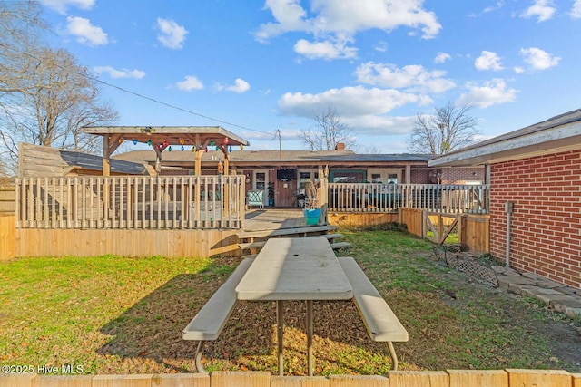 rear view of house with a lawn and a wooden deck