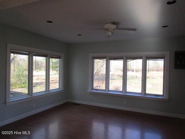 unfurnished room featuring a ceiling fan, visible vents, baseboards, and wood finished floors