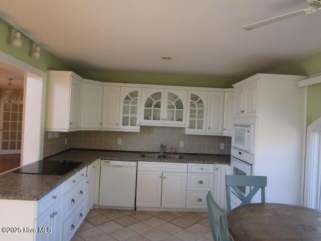 kitchen featuring white appliances, tasteful backsplash, white cabinetry, and a sink