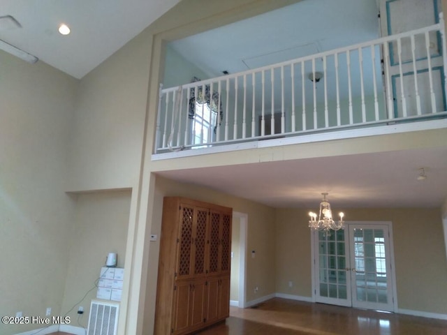 entryway with hardwood / wood-style flooring, a towering ceiling, and an inviting chandelier