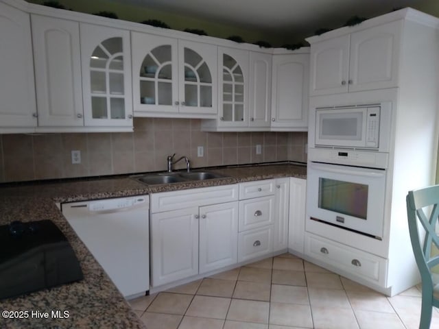 kitchen with sink, backsplash, white cabinets, light tile patterned floors, and white appliances