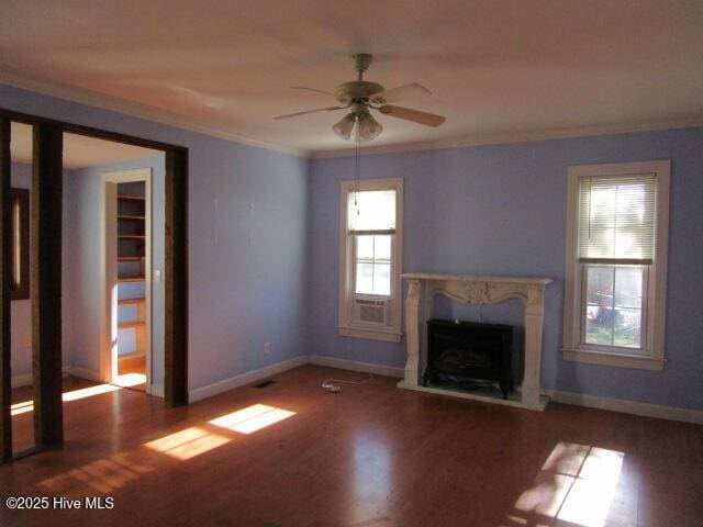 unfurnished living room with a premium fireplace, ornamental molding, a ceiling fan, wood finished floors, and baseboards