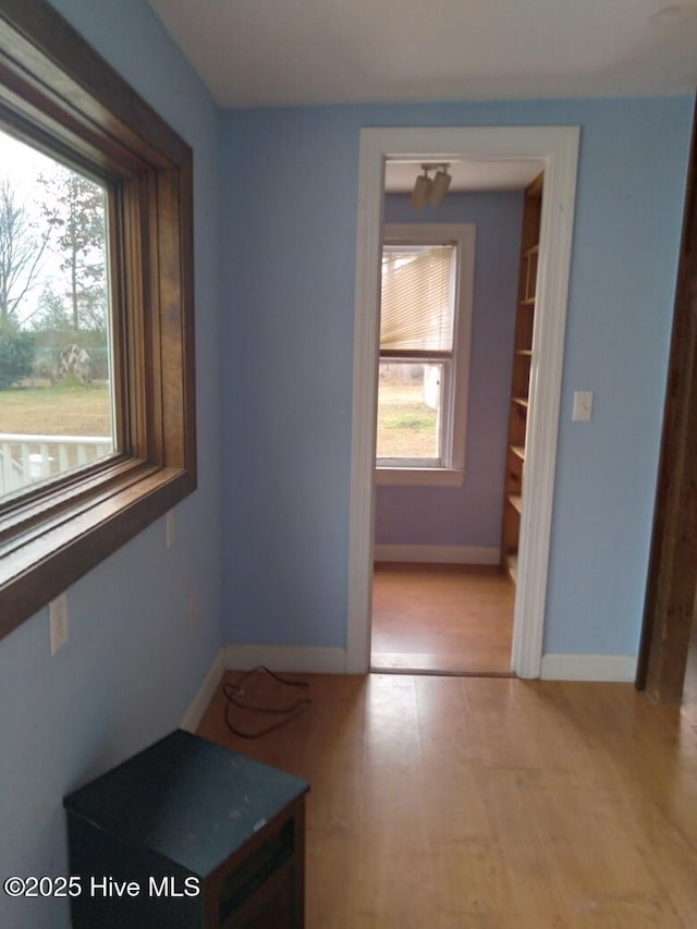 hallway featuring light wood-style flooring and baseboards