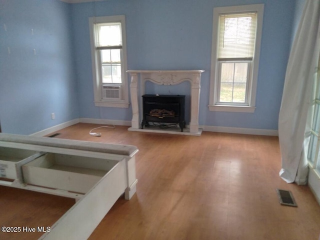 unfurnished living room featuring cooling unit, plenty of natural light, a premium fireplace, and light hardwood / wood-style floors