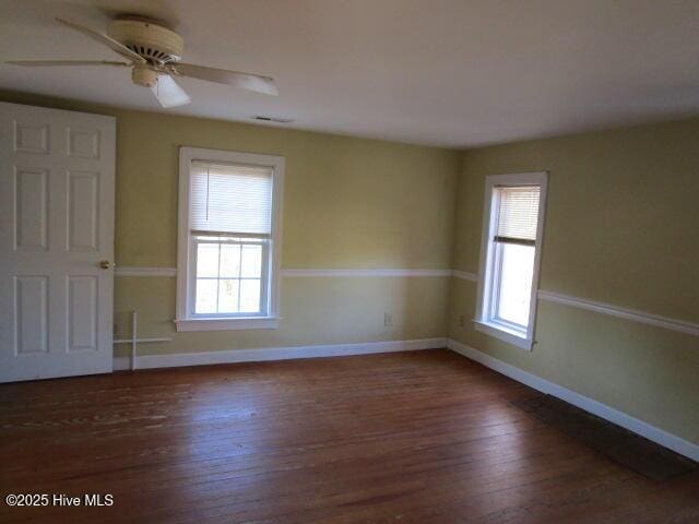 empty room with a ceiling fan, visible vents, baseboards, and wood finished floors