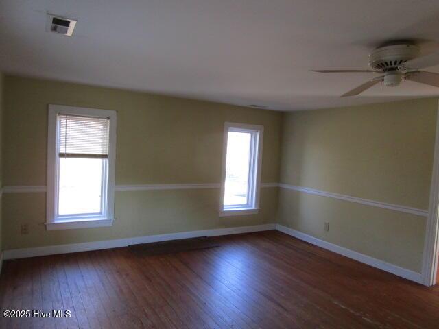 spare room with visible vents, baseboards, hardwood / wood-style flooring, and a healthy amount of sunlight