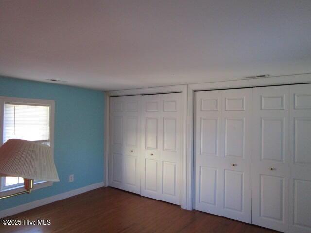 unfurnished bedroom with visible vents, baseboards, and wood finished floors