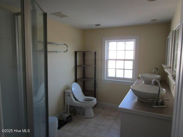 full bath featuring visible vents, double vanity, a sink, and toilet