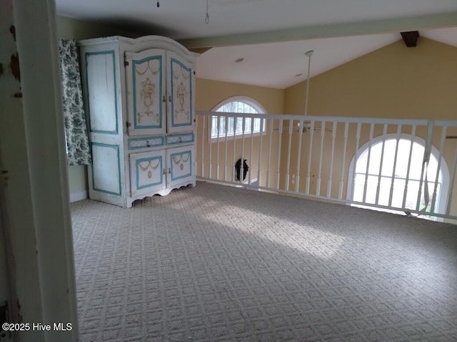 carpeted spare room featuring lofted ceiling with beams and ceiling fan