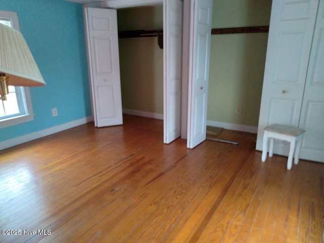 unfurnished bedroom featuring hardwood / wood-style floors and two closets