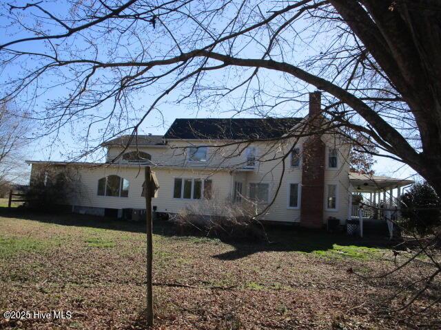 back of property featuring a lawn and a chimney