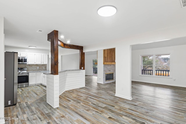 interior space with tasteful backsplash, white cabinets, light wood-type flooring, and appliances with stainless steel finishes