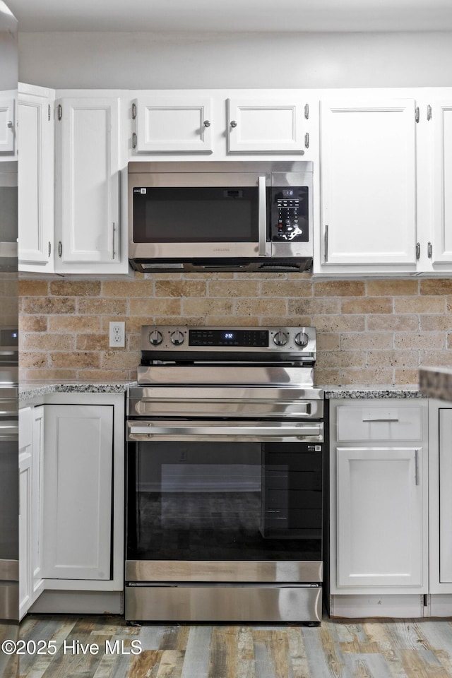 kitchen featuring light stone countertops, appliances with stainless steel finishes, and white cabinetry