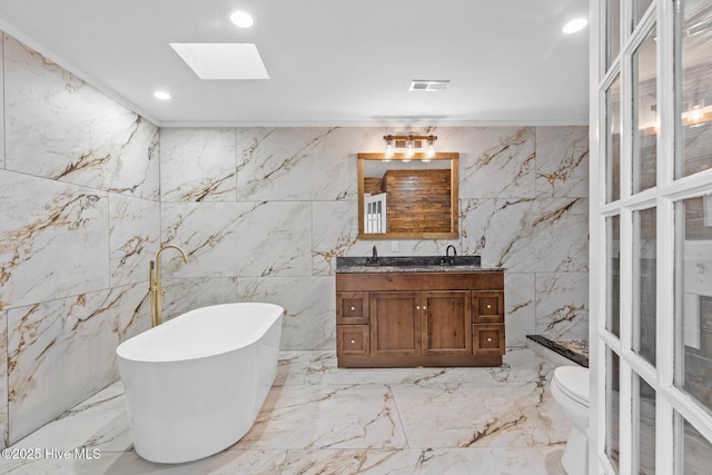 bathroom with vanity, a skylight, a washtub, toilet, and ornamental molding