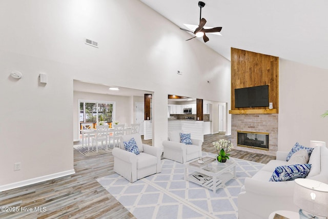 living room with high vaulted ceiling, a brick fireplace, ceiling fan, and hardwood / wood-style flooring