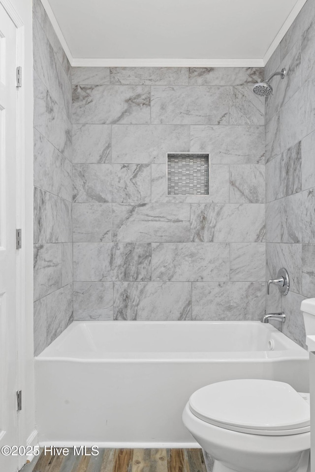 bathroom featuring hardwood / wood-style flooring, crown molding, tiled shower / bath combo, and toilet